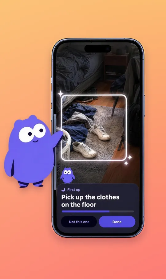 Mopkin pointing at its own app screen, where a glowing spotlight frames clothes and sneakers on a rug under the words First up: Pick up the clothes on the floor.
